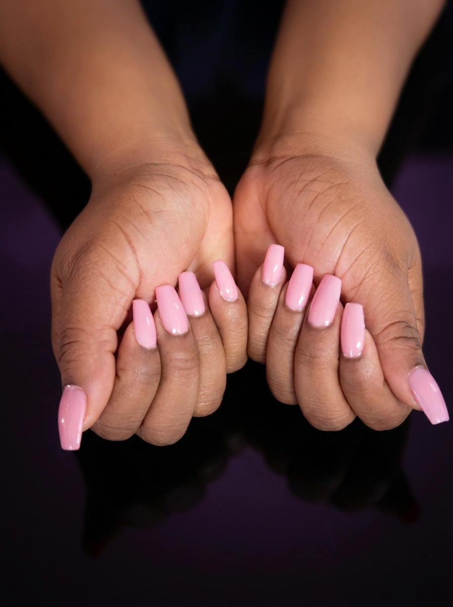 Long glossy pink coffin nails displayed in an editorial beauty photo